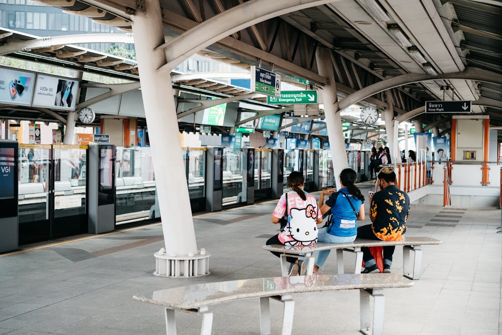 Hire Digital Advertising Agency Near Me - People sitting on a railway station platform, waiting for the train in an urban setting.